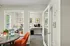 Inviting office space with a modern glass door, a cozy orange chair, and a welcoming coffee station offering a warm ambiance.