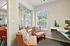 Charming and cozy sitting area with bright orange chairs overlooking a sunlit garden, perfect for relaxation or conversation.