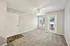 Bright, spacious room with plush carpet, ceiling fan, and large windows offering abundant natural light.