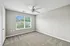 Bright and airy bedroom with plush carpet and large window offering lush green views.