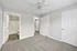 Inviting bedroom with plush carpet, ceiling fan, and ensuite bathroom, showcasing modern design and comfort.
