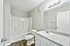 Bright and modern bathroom with chic wood flooring, sleek white fixtures, and a spacious vanity, perfect for relaxation and comfort.