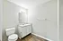 Bright, modern bathroom featuring sleek white cabinetry, a large mirror, and elegant wood flooring.