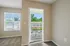 Bright apartment bedroom featuring plush carpet and a private balcony with lush green views.