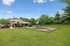 Charming residential area with a well-maintained lawn, inviting playground, and cozy red-brick building surrounded by lush greenery, perfect for family living.