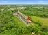 Scenic aerial view of a serene apartment complex nestled in lush greenery, highlighting ample parking and a vibrant community atmosphere.