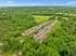 Expansive aerial view of a serene apartment complex nestled amidst lush greenery, offering tranquil living with convenient parking and scenic surroundings.