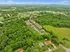 Captivating aerial view of a serene apartment complex nestled within lush green landscapes, offering tranquility and convenient access to nearby neighborhoods.