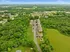 Scenic aerial view of a serene apartment complex surrounded by lush greenery and open fields, offering tranquility and picturesque landscapes.