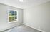 Bright, sunlit room with a large window and plush carpeting, perfect for a cozy bedroom or home office.
