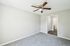 Bright and airy bedroom with modern ceiling fan, plush carpet, and sleek closet doors, offering comfort and style.