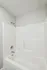 Pristine white bathtub with modern chrome fixtures in a spacious bathroom.