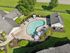 Charming aerial view of a serene community pool area surrounded by lush greenery, cozy lounging chairs, and charming poolside umbrellas, perfect for relaxation and recreation.