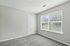 Bright and inviting bedroom featuring soft gray carpet and large windows with natural light.