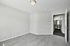 Bright and spacious bedroom featuring plush carpeting and a modern light fixture, adjacent to a sleek bathroom.