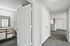 Modern apartment hallway with sleek laminate floors leading to a bright, contemporary bathroom featuring a spacious vanity.