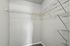 Spacious walk-in closet with organized shelving and neutral walls, perfect for ample storage.