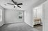 Bright bedroom with plush carpet and a modern ceiling fan, connected to an elegant en-suite bathroom with ample natural light.