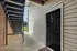 Inviting apartment entrance with sleek black door under a modern staircase, highlighting a welcoming exterior.
