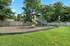 Charming playground with a spiral slide and swings, nestled in a spacious, fenced-in yard surrounded by lush greenery, ideal for family fun.