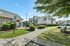 Charming apartment complex with well-maintained landscaping, reserved parking, and inviting green spaces on a sunny day.