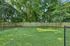 Spacious backyard with lush greenery and fenced area, ideal for relaxation and outdoor activities.