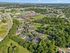 Scenic aerial view of tranquil apartment community surrounded by lush greenery and well-connected roads, offering a serene living atmosphere.