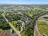Scenic aerial view of lush green landscape with a charming residential community nestled among trees and curving roads, offering tranquil living.