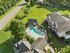 Stunning aerial view of modern apartment complex with a sparkling swimming pool surrounded by lush green landscaping and expansive open spaces.