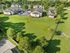 Charming apartment complex surrounded by lush green lawns and mature trees, offering a serene residential setting with ample parking space.