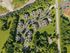 Stunning aerial view of a lush, green residential complex featuring modern apartments, ample parking, and inviting pathways surrounded by vibrant trees.