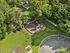Charming aerial view of a serene community playground surrounded by lush green trees and a well-maintained lawn, ideal for family living.