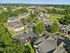 Aerial view of charming apartment complex nestled in lush greenery with spacious parking and scenic surroundings.