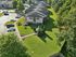 Aerial view of a charming residential community with lush green lawns, well-maintained pathways, and ample parking spaces surrounded by mature trees.