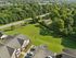 Aerial view of modern apartments surrounded by lush greenery, offering a tranquil suburban setting with ample open space and convenient parking access.