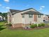 Charming apartment building with modern brick and siding exterior, surrounded by lush green lawns and well-maintained landscaping.