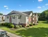 Charming multi-unit apartment building with beautifully landscaped lawns and inviting architecture under a clear blue sky.