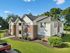 Charming two-story apartment building with brick facade, surrounded by lush green lawns and mature trees, creating a welcoming and serene living environment.