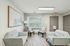 Bright, modern sitting area featuring stylish gray sofas, elegant armchairs, and chic wall art, offering a cozy atmosphere with natural light and contemporary decor.