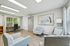 Bright and modern office space with elegant seating, a stylish desk by a large window, and contemporary artwork on the wall.