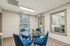 Bright and inviting office entrance with modern blue chairs around a glass table, complemented by elegant patterned curtains and natural light.