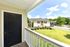 Inviting balcony view showcasing a charming residential neighborhood with manicured lawns and sunny skies.