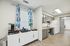 Charming kitchen area with sleek gray cabinets, modern appliances, and a vibrant coffee nook accented by floral curtains.
