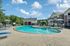 Inviting community pool area surrounded by lounge chairs and umbrellas, perfect for relaxation and leisure under a bright blue sky.