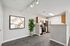 Contemporary kitchen with sleek appliances, modern cabinetry, and artistic decor, complemented by gray flooring and bright lighting.