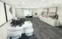 Inviting and modern office space with stylish decor, featuring a sleek white desk with a computer setup, elegant artwork, and a cozy seating area with a contemporary dining table.
