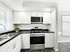 Modern kitchen with sleek stainless steel appliances, elegant white cabinetry, and a spacious dual sink setup.
