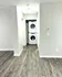 Modern apartment interior featuring sleek hardwood flooring and a convenient in-unit laundry area with stacked washer and dryer.