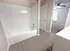 Sleek bathroom with white tiled bathtub, modern fixtures, and elegant flooring leading into a sunlit carpeted room.
