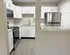 Modern apartment kitchen with sleek white cabinetry, stainless steel appliances, and elegant marble countertops.